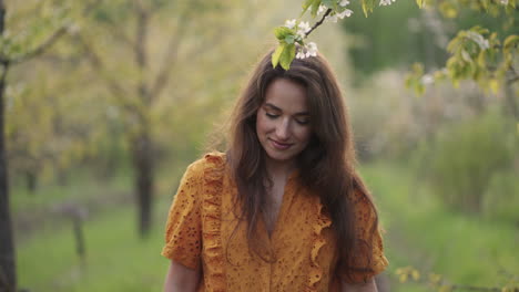 beautiful-young-woman-is-walking-alone-in-blooming-orchard-in-spring-charming-lady-with-smile